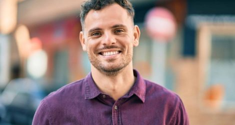 Young hispanic man smiling happy standing at the city.