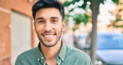 Young latin man smiling happy walking at the city.
